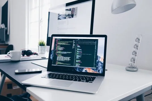 Лаптоп с програмен код на светло работно бюро